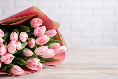 Photo of Beautiful bouquet of fresh pink tulips on light wooden table, closeup. Space for text