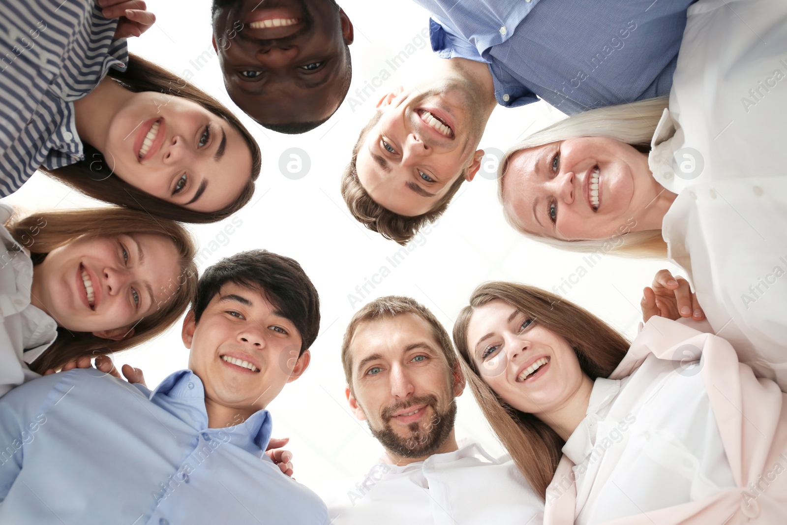 Photo of People standing together against light background, bottom view. Unity concept