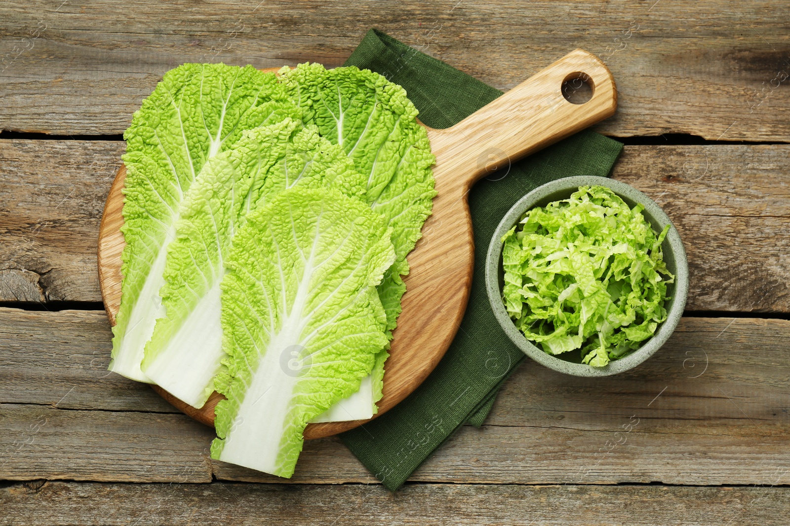 Photo of Cut fresh Chinese cabbage and leaves on wooden table, top view