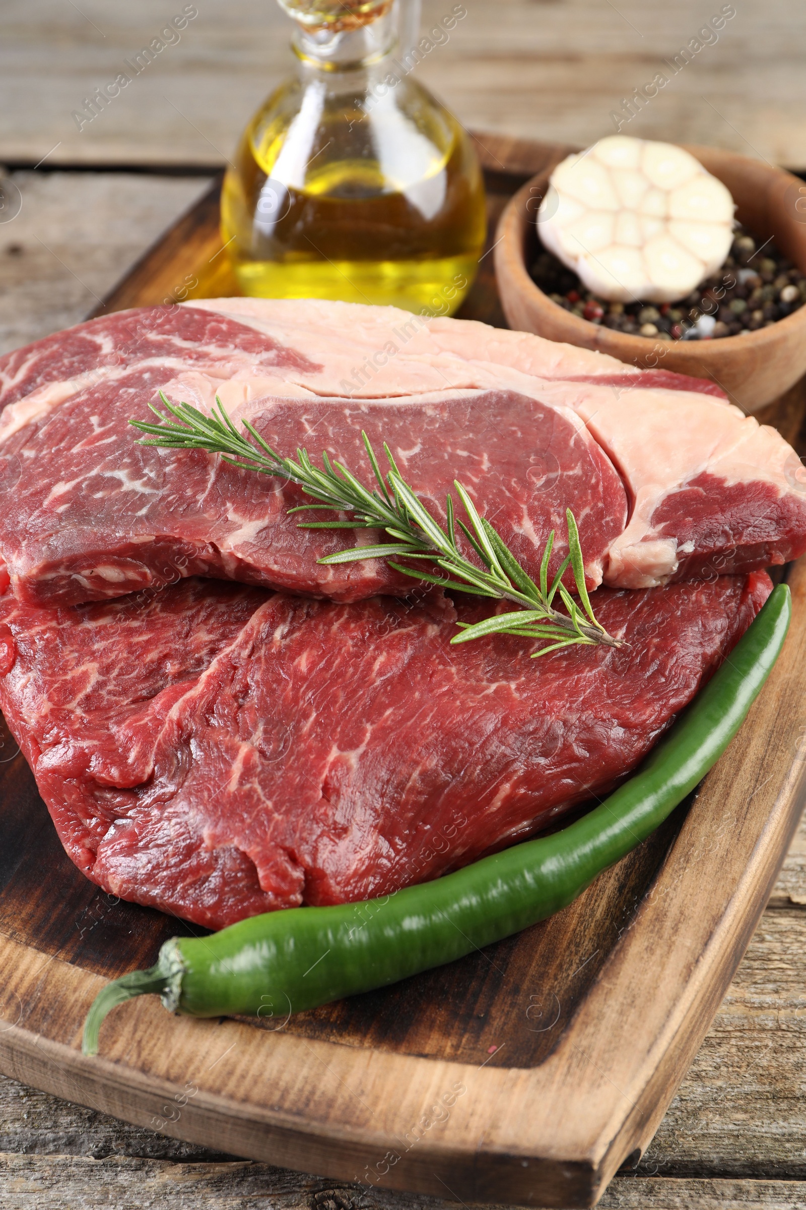 Photo of Fresh raw beef cut with spices and oil on wooden table, closeup