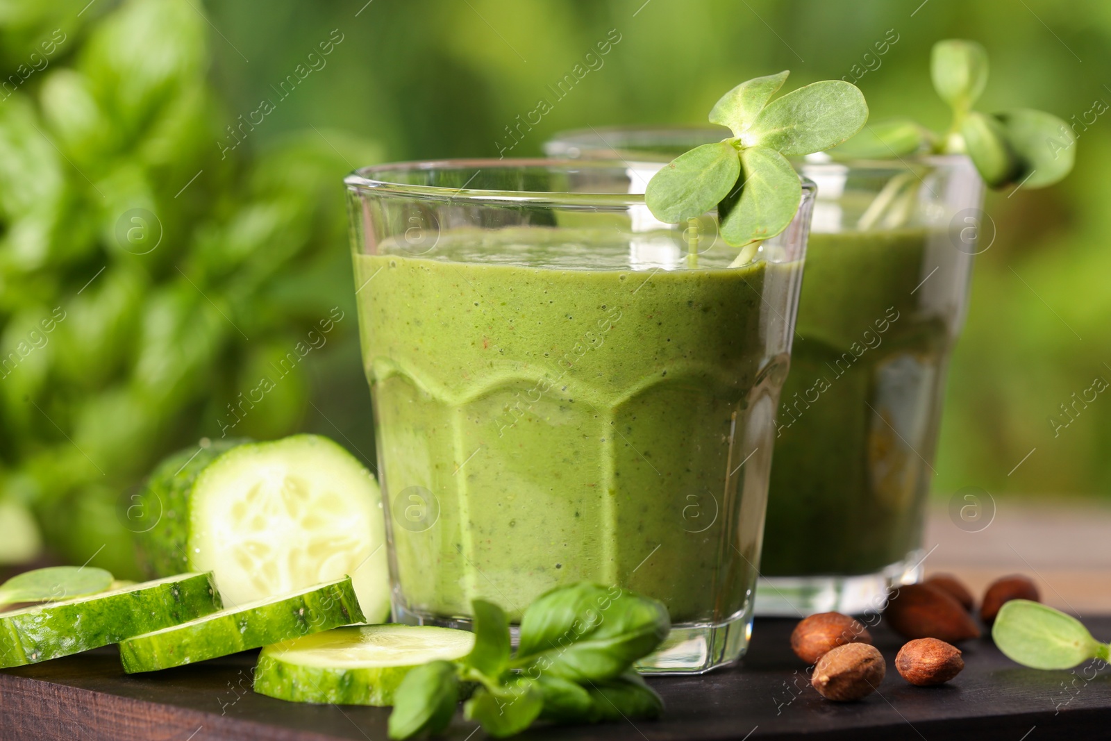Photo of Glasses of fresh green smoothie and ingredients on wooden table, closeup
