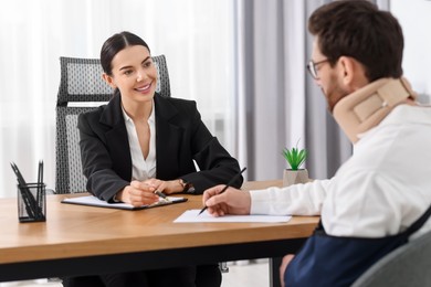 Injured man signing document in lawyer's office, selective focus