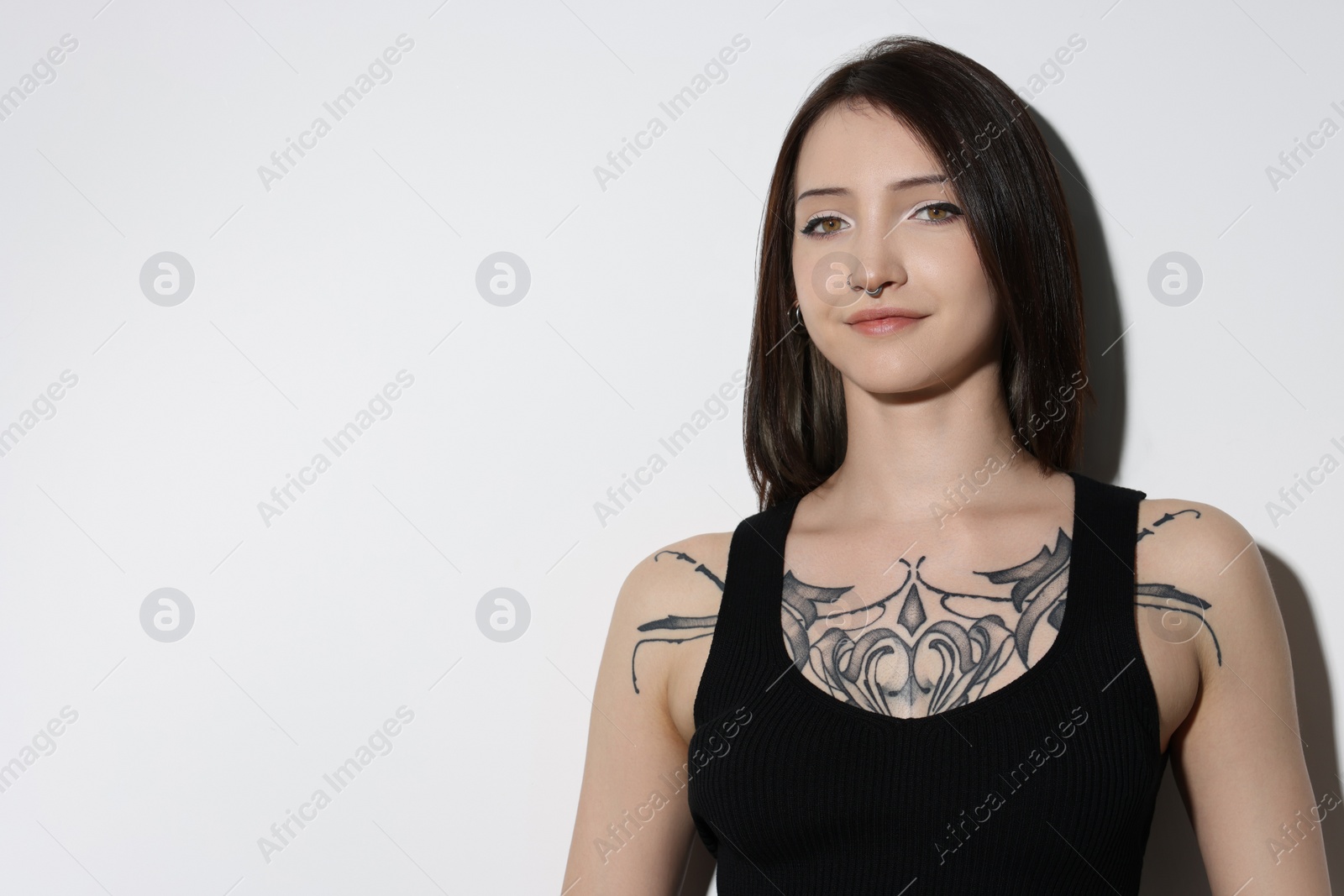 Photo of Portrait of beautiful tattooed woman on light background. Space for text