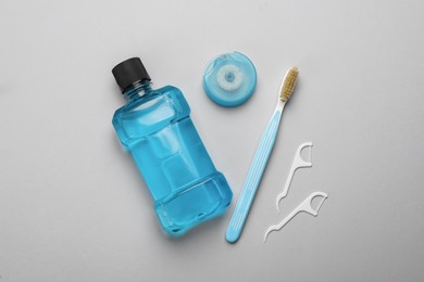 Photo of Mouthwash, toothbrush and dental floss on light grey background, flat lay