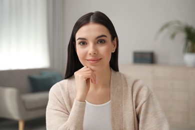 Photo of Beautiful young woman conducting webinar in room, camera view