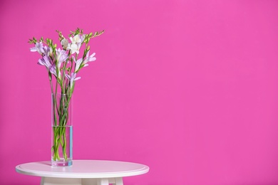 Photo of Beautiful fragrant freesia flowers in vase and space for text on color background