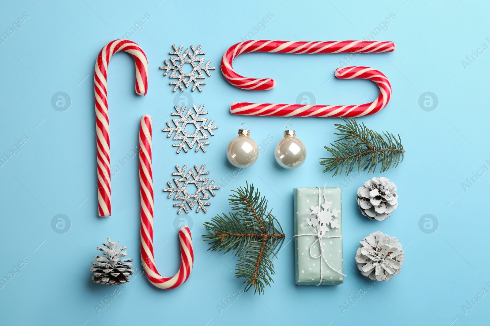 Photo of Flat lay composition with candy canes and Christmas decor on light blue background