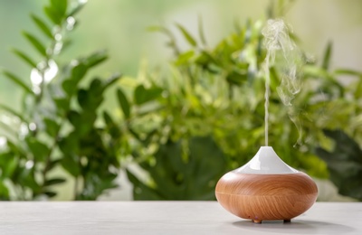 Aroma oil diffuser on table against blurred background. Air freshener