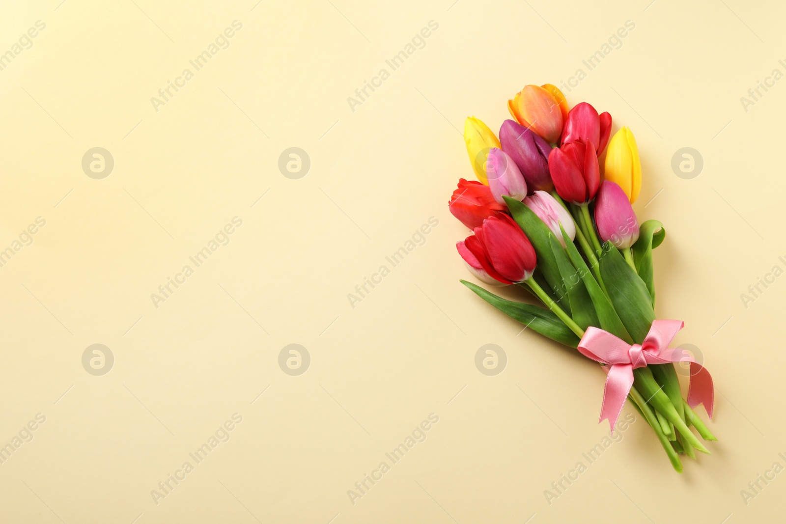 Photo of Beautiful bouquet of spring tulip flowers on color background, top view. Space for text