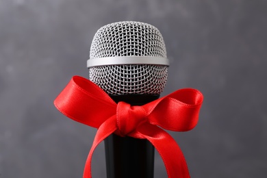 Photo of Microphone with red bow on grey background. Christmas music