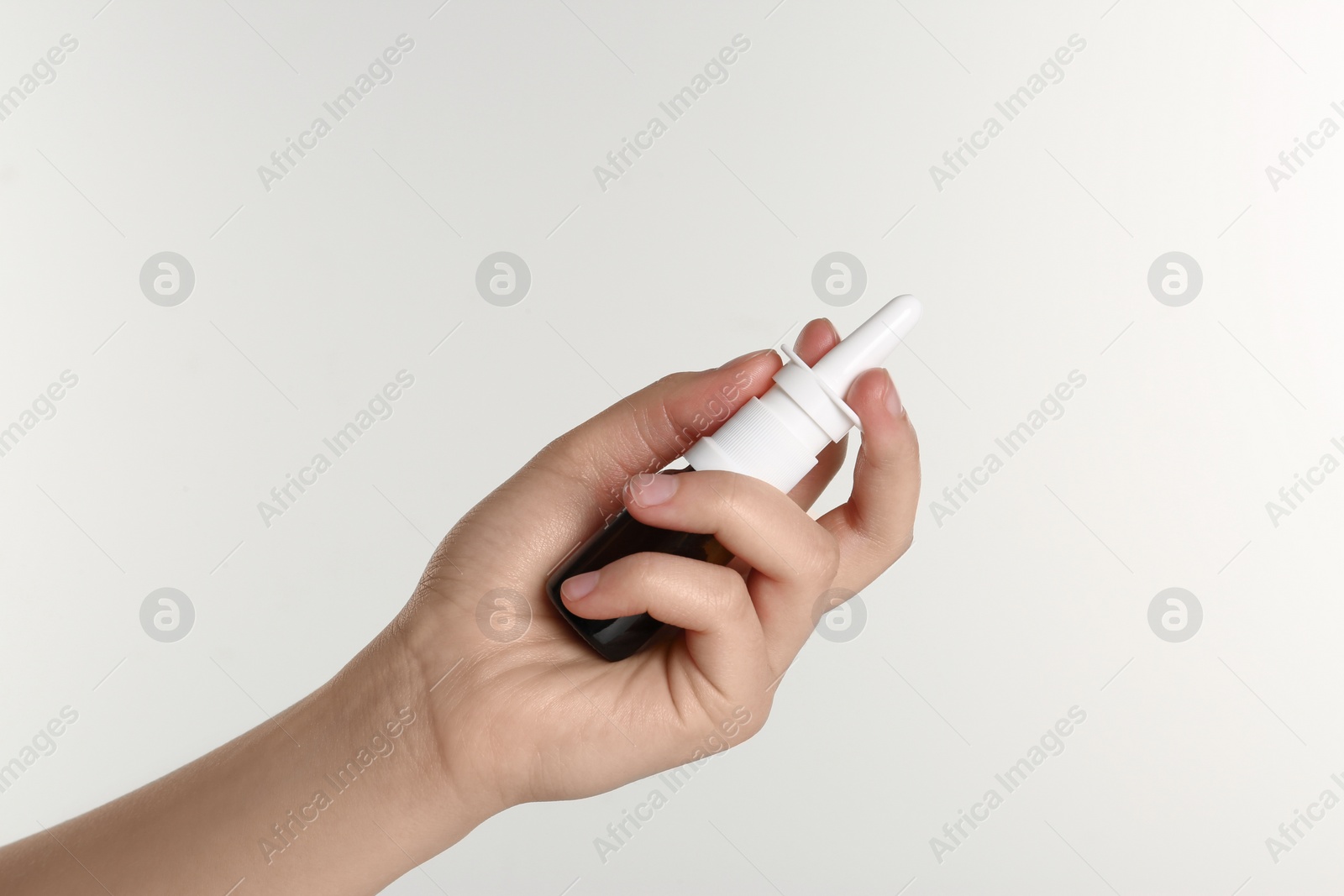 Photo of Woman holding nasal spray on white background, closeup