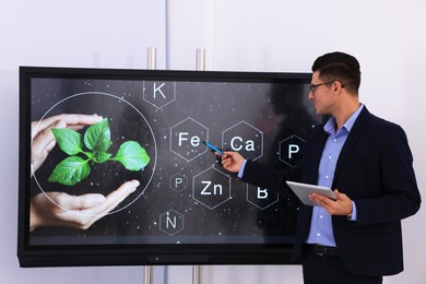 Photo of Teacher using interactive board in classroom during lesson