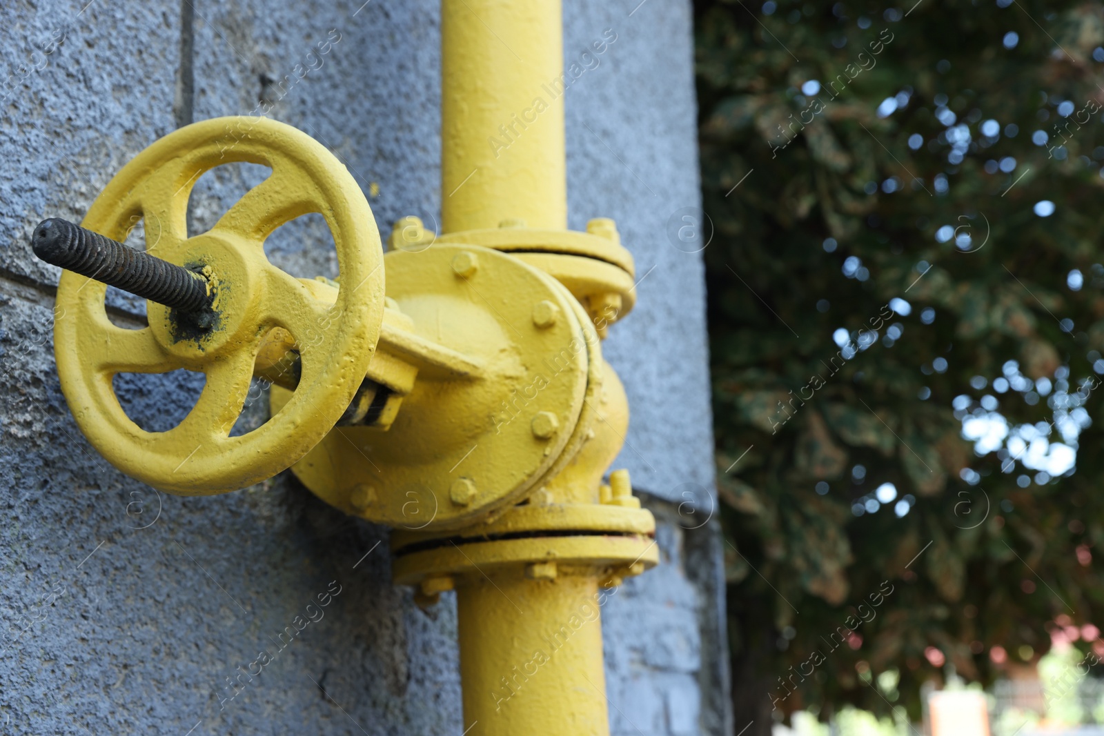 Photo of Yellow gas pipe on grey wall outdoors, closeup. Space for text