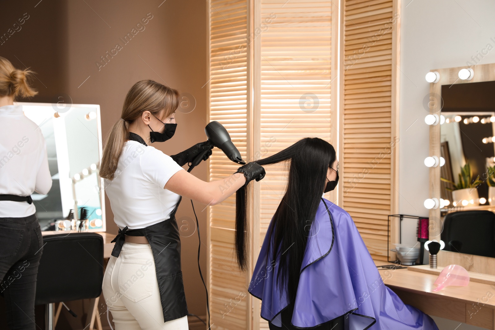 Photo of Professional stylist working with client in beauty salon. Hairdressing services during Coronavirus quarantine