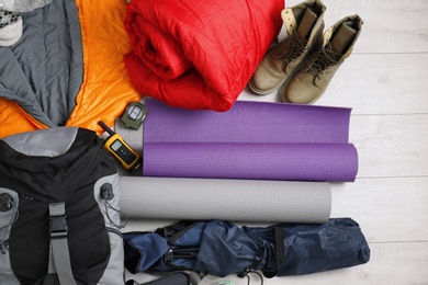 Flat lay composition with sleeping bags and camping equipment on wooden background