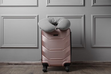 Photo of Striped travel pillow on suitcase near light wall indoors