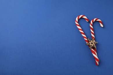 Photo of Flat lay composition with candy canes and snowflake on blue background. Space for text