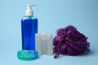 Purple shower puff and cosmetic products on light blue background