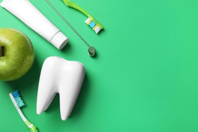 Photo of Flat lay composition with toothbrushes and holder on green background, space for text