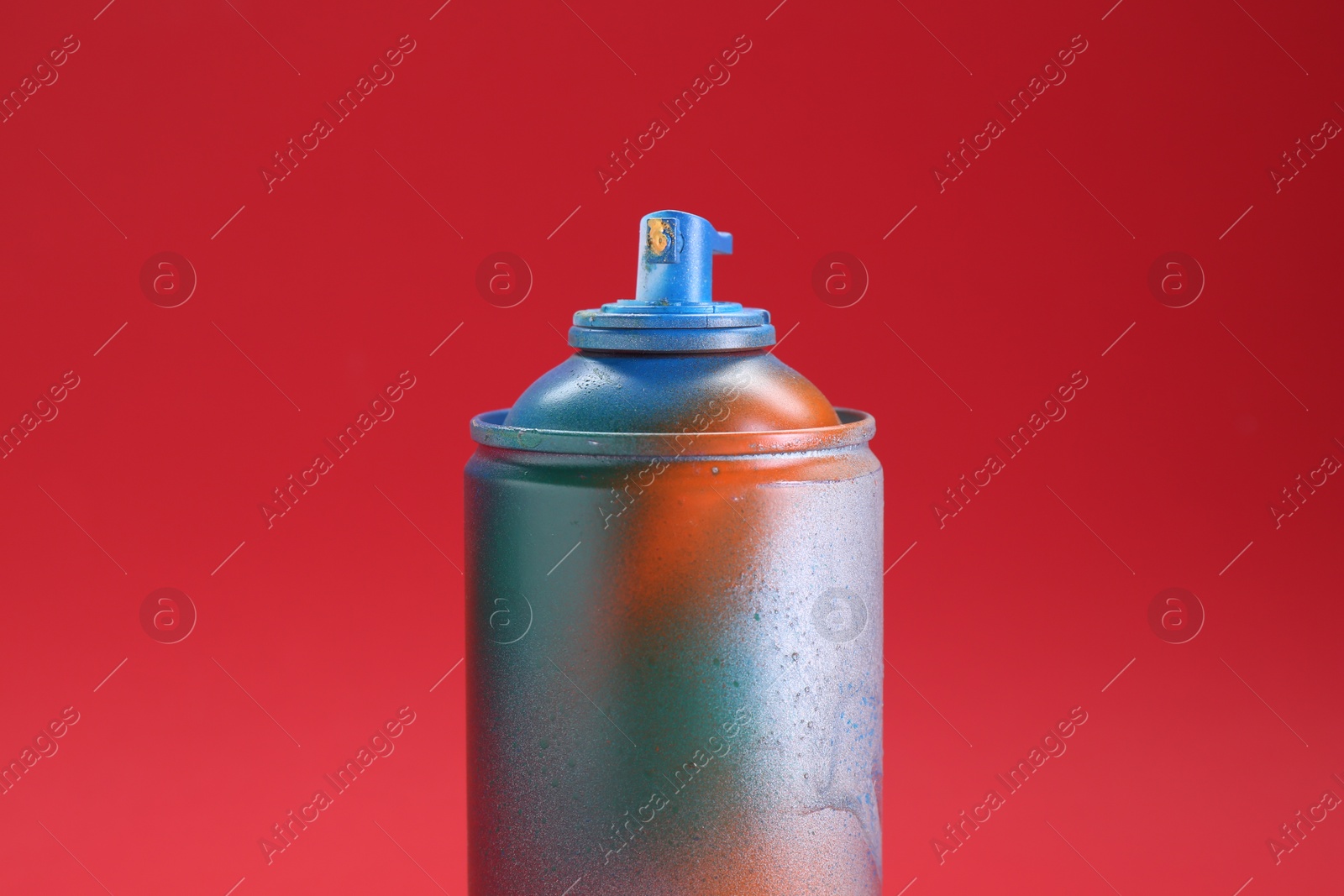 Photo of One can of bright spray paint on red background, closeup