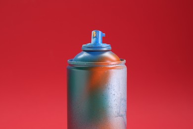 One can of bright spray paint on red background, closeup