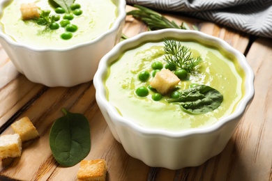 Fresh vegetable detox soup made of green peas and spinach with croutons served on table