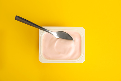 Tasty organic yogurt on yellow background, top view