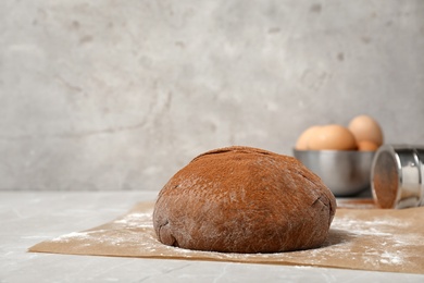 Photo of Fresh raw dough ball with cocoa powder on kitchen table