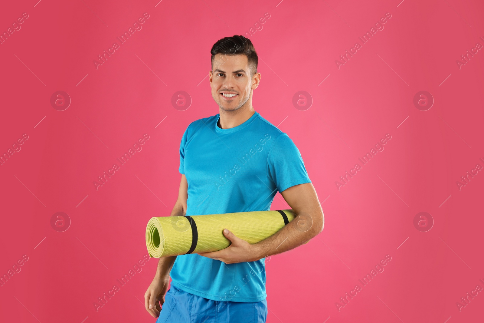 Photo of Handsome man with yoga mat on pink background