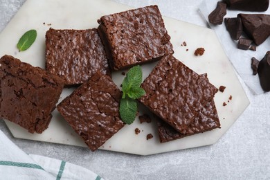 Delicious chocolate brownies with fresh mint on grey table, flat lay