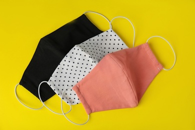 Photo of Homemade protective face masks on yellow background, flat lay