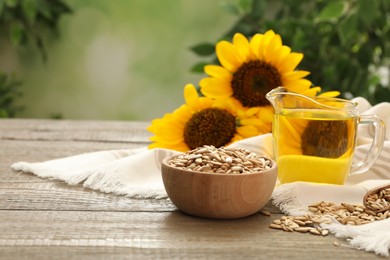 Photo of Sunflower oil and seeds on wooden table against blurred background, space for text