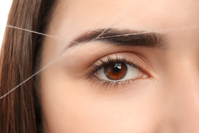 Photo of Young woman having professional eyebrow correction procedure, closeup