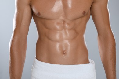Photo of Shirtless man with slim body and towel wrapped around his hips on grey background, closeup