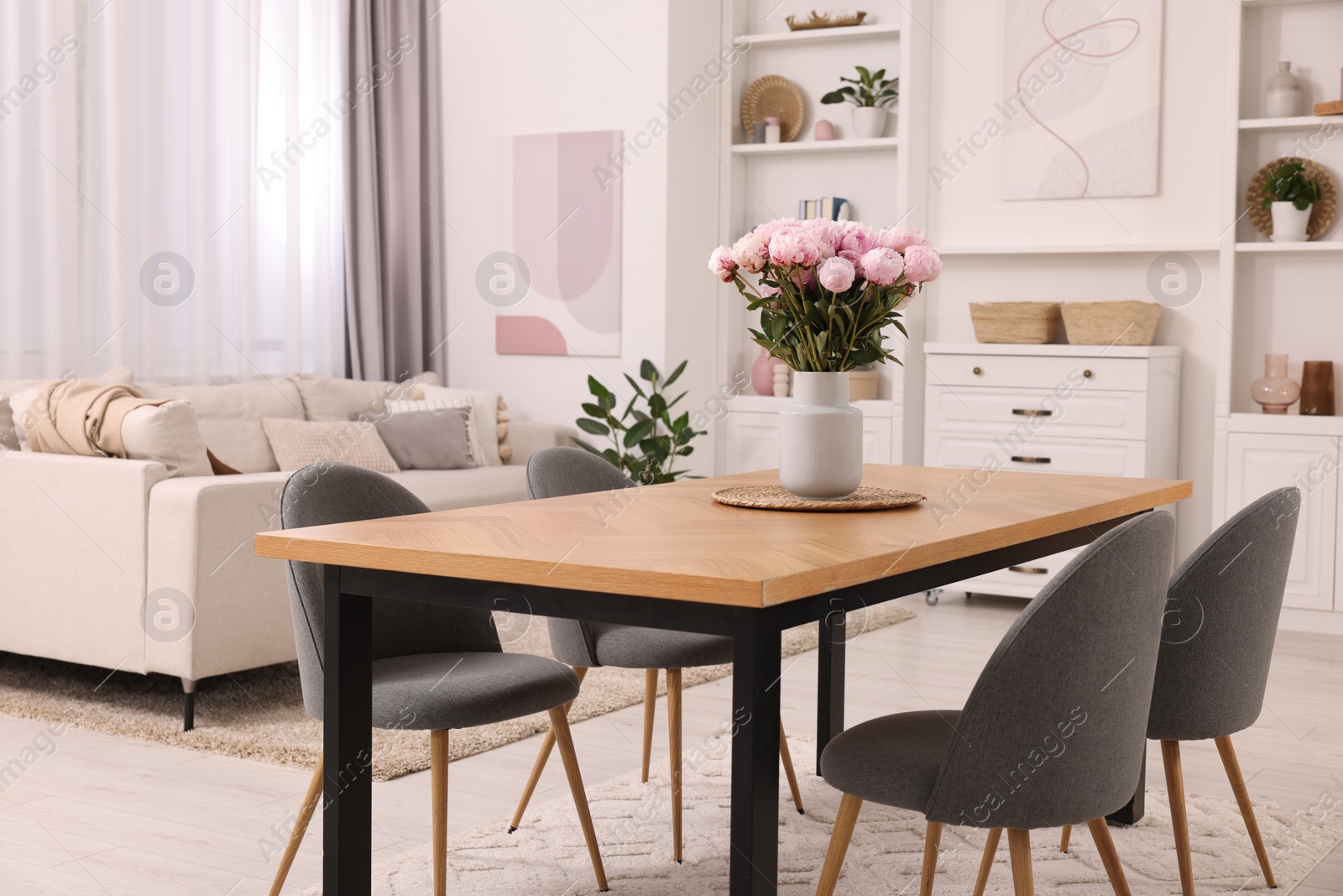 Photo of Stylish dining room with cosy furniture and flowers