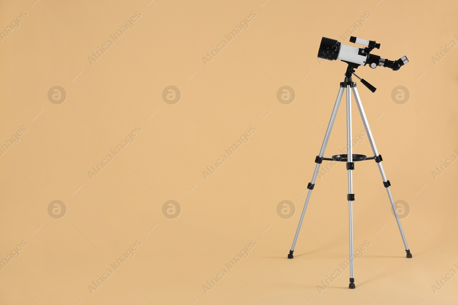 Photo of Tripod with modern telescope on beige background, space for text