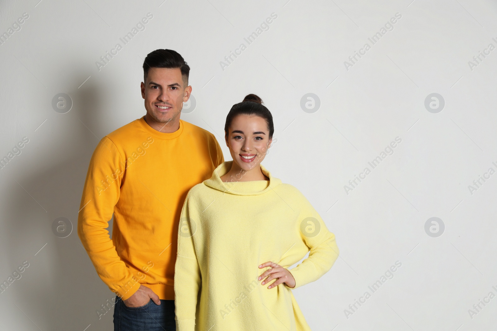 Photo of Happy couple wearing yellow warm sweaters on white background. Space for text