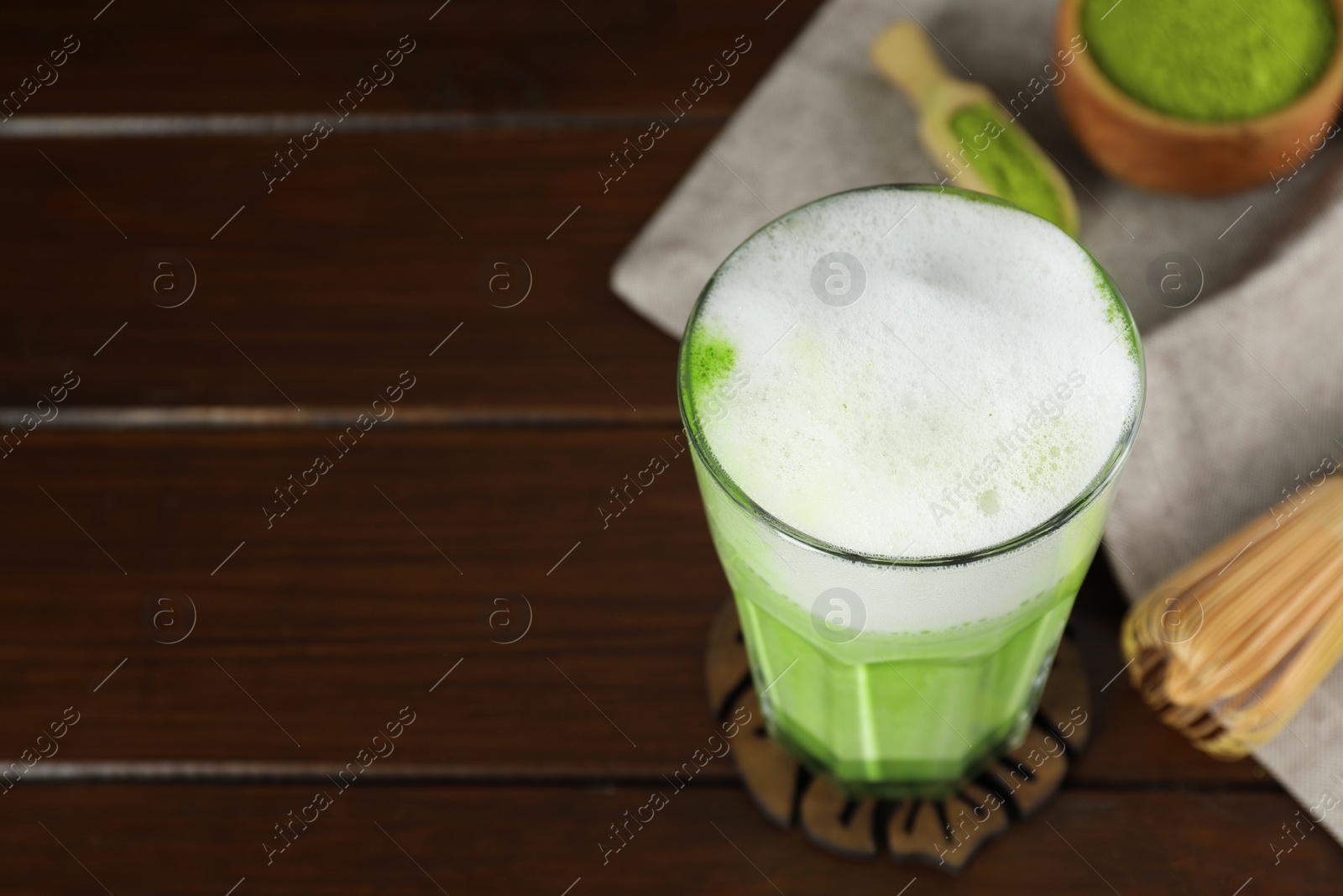Photo of Glass of tasty matcha latte on wooden table, closeup. Space for text