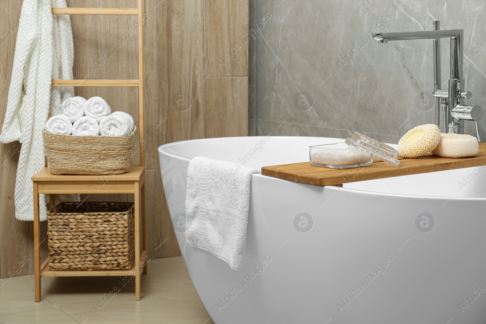 Photo of Soft bath towel and personal care products on tub tray in bathroom