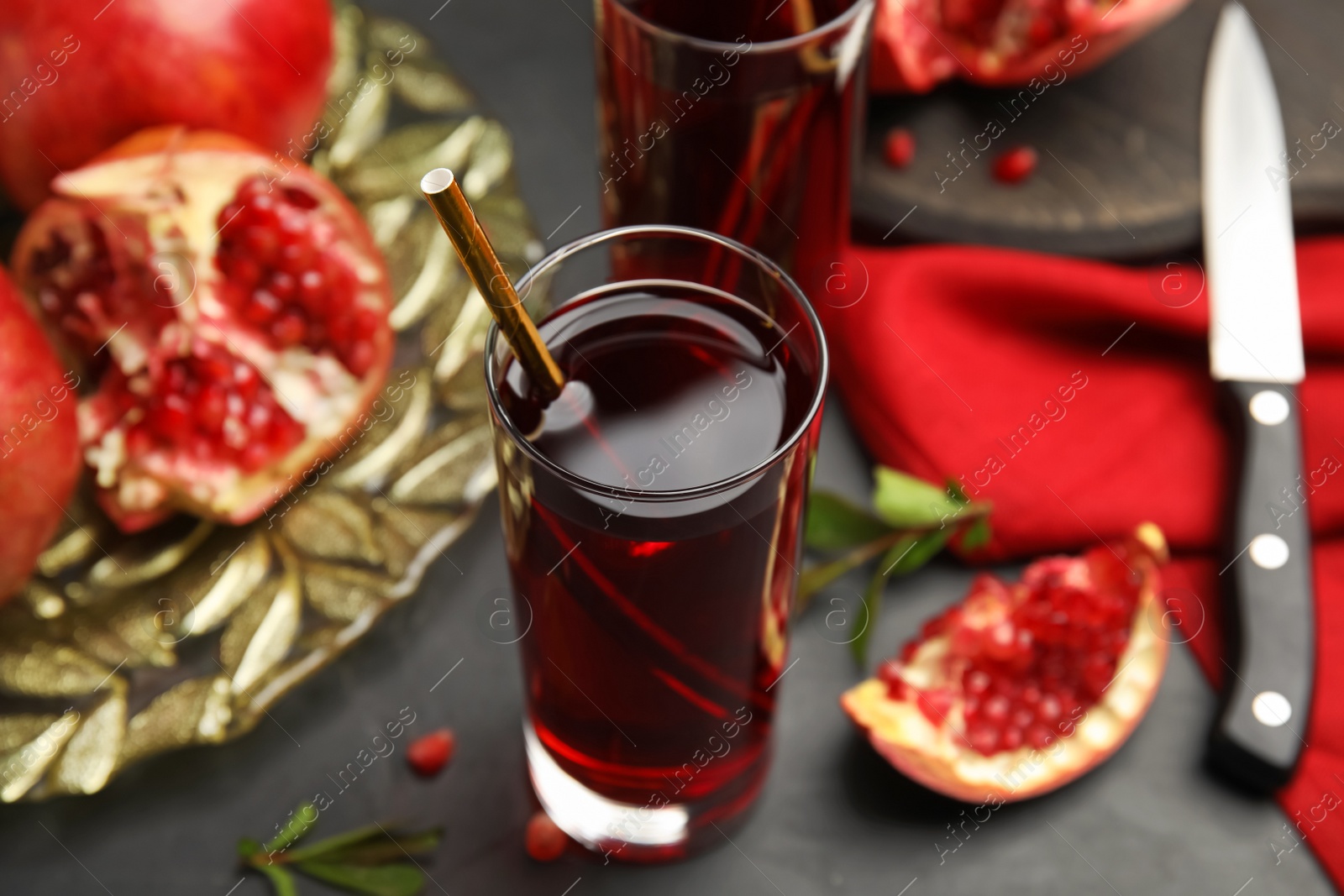 Photo of Pomegranate juice and fresh fruits on black table