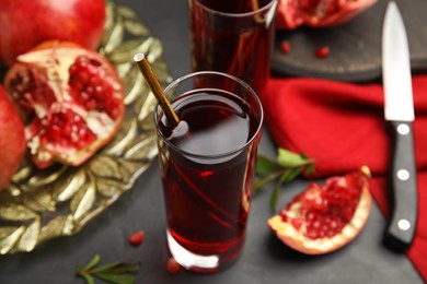 Photo of Pomegranate juice and fresh fruits on black table