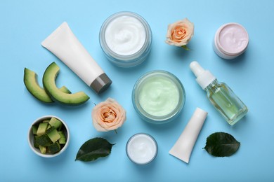 Photo of Body cream and other cosmetic products with ingredients on light blue background, flat lay