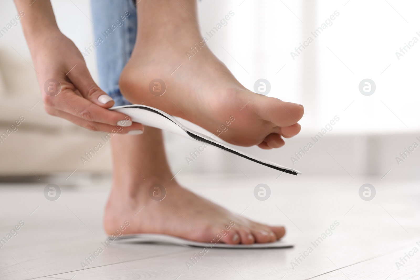 Photo of Woman fitting orthopedic insole at home, closeup
