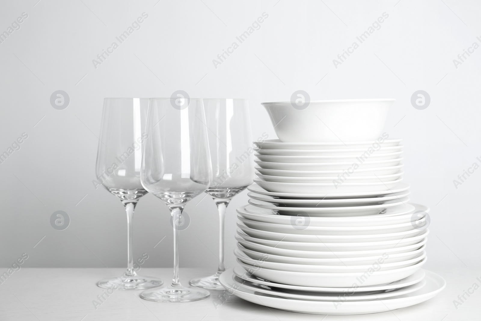 Photo of Stack of clean plates and glasses on white background