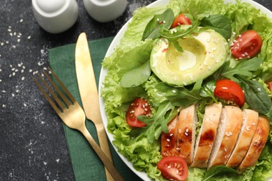 Delicious salad with chicken, cherry tomato and avocado served on grey textured table, flat lay