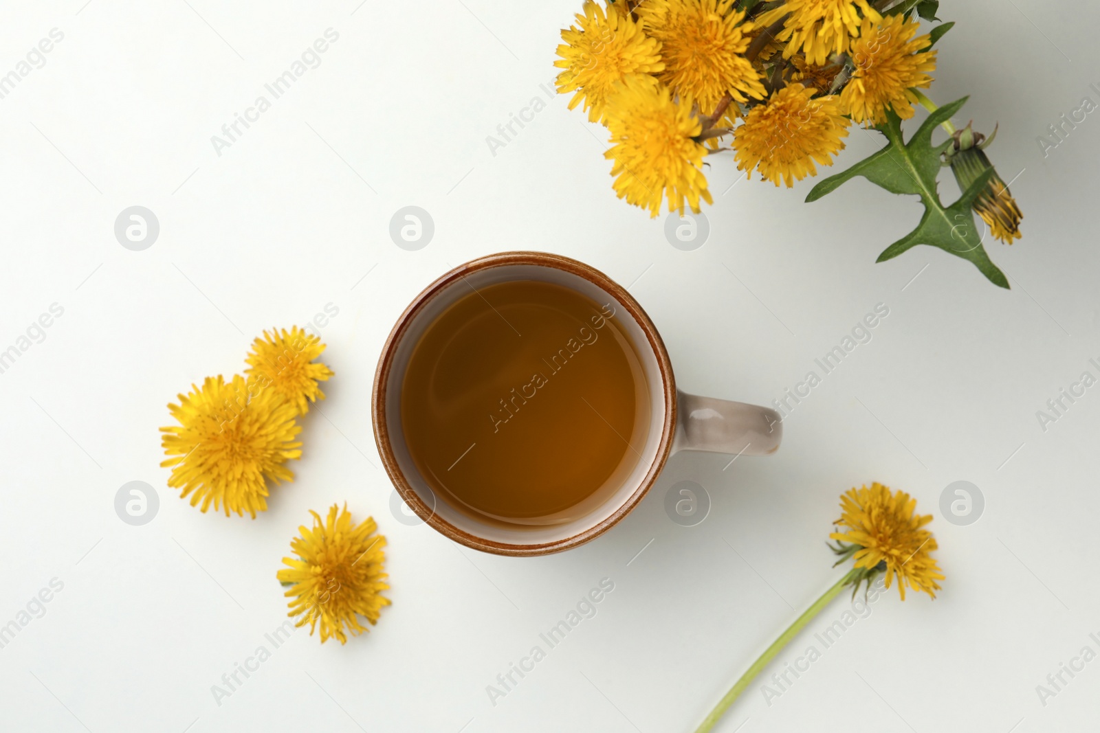 Photo of Delicious fresh tea and beautiful dandelion flowers on white background, top view