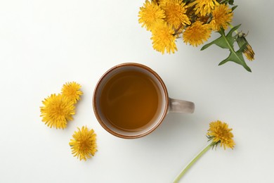Photo of Delicious fresh tea and beautiful dandelion flowers on white background, top view
