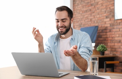 Young man using video chat on laptop in home office