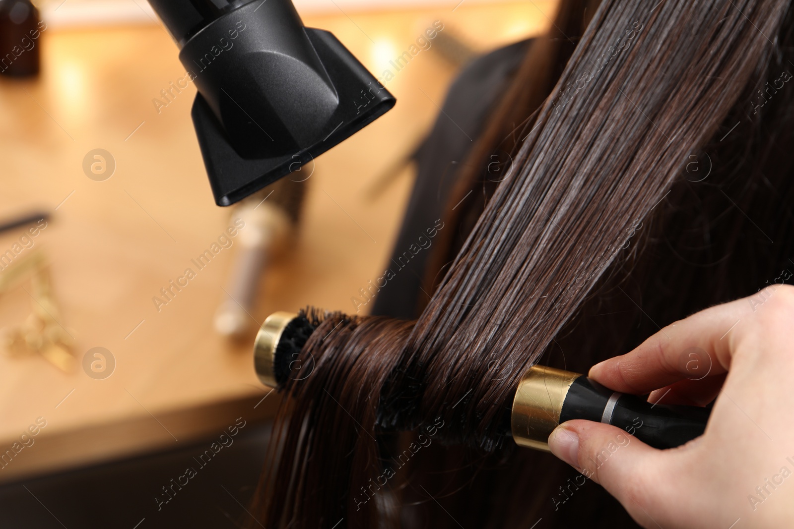 Photo of Hairdresser blow drying client's hair in salon, closeup