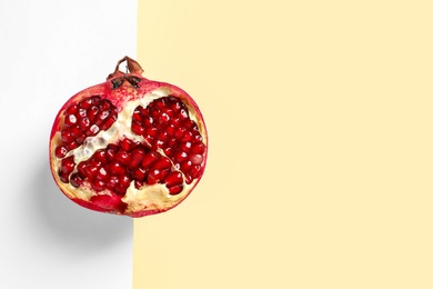 Half of ripe pomegranate on color background, top view with space for text